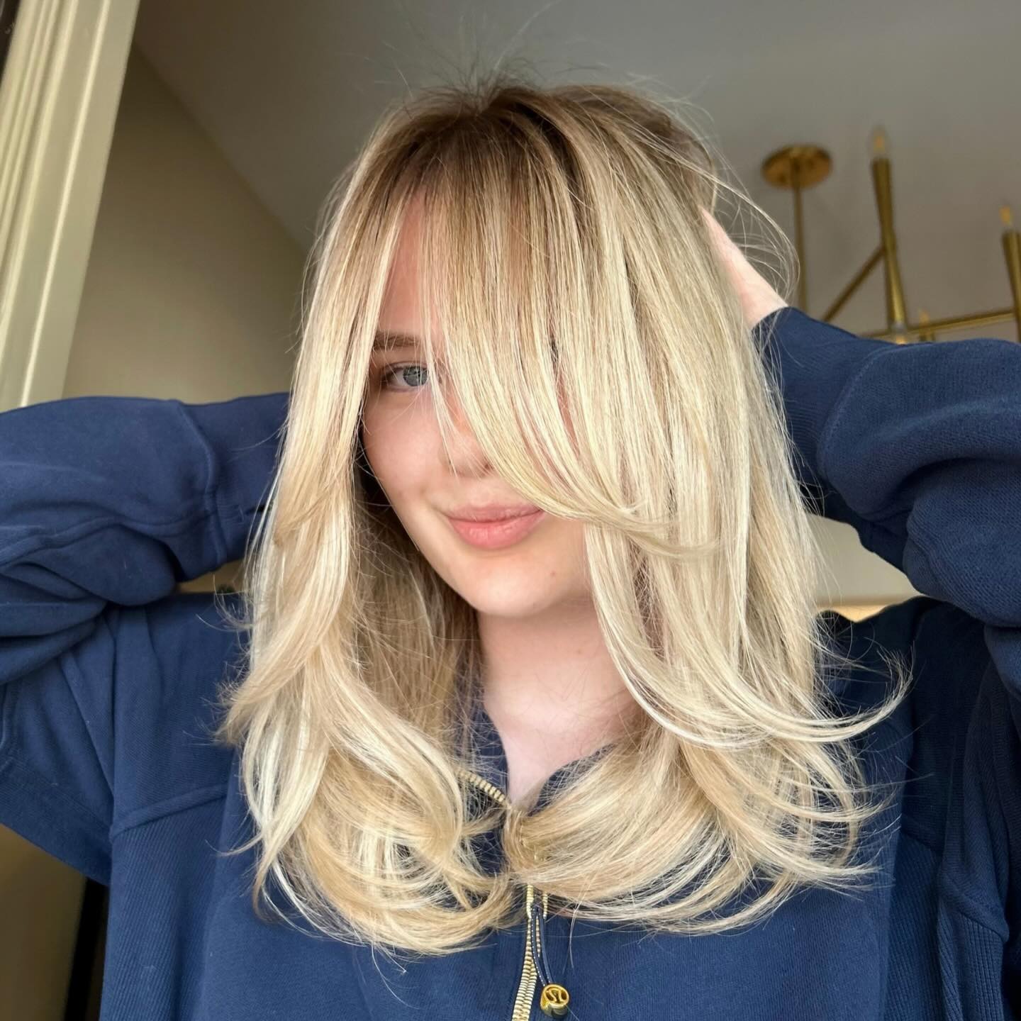 Smiling Woman with Honey Blonde Butterfly Cut and Long Curtain Bangs