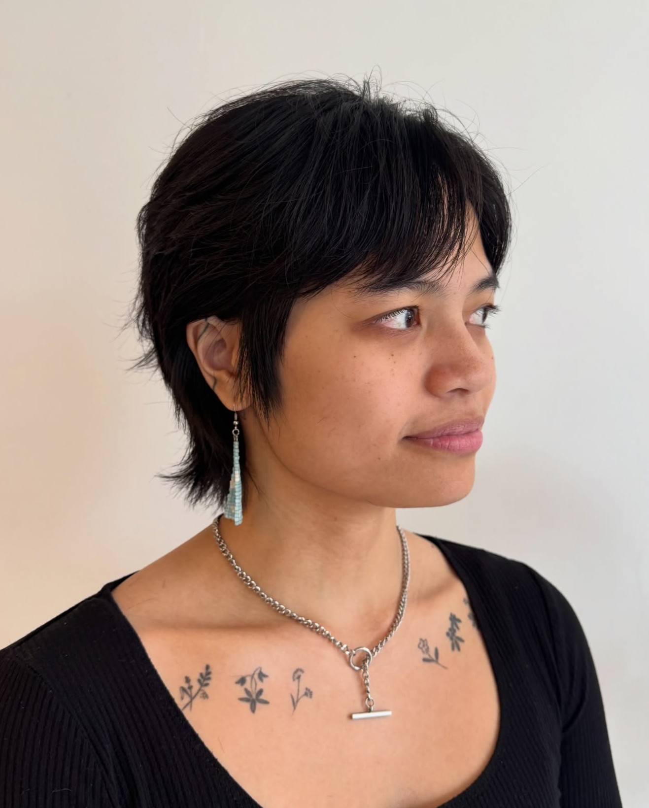 Shaggy Dark Pixie Wolf Cut Mix with Textured Layers and Long Wispy Sideburns Shown from a Side Profile