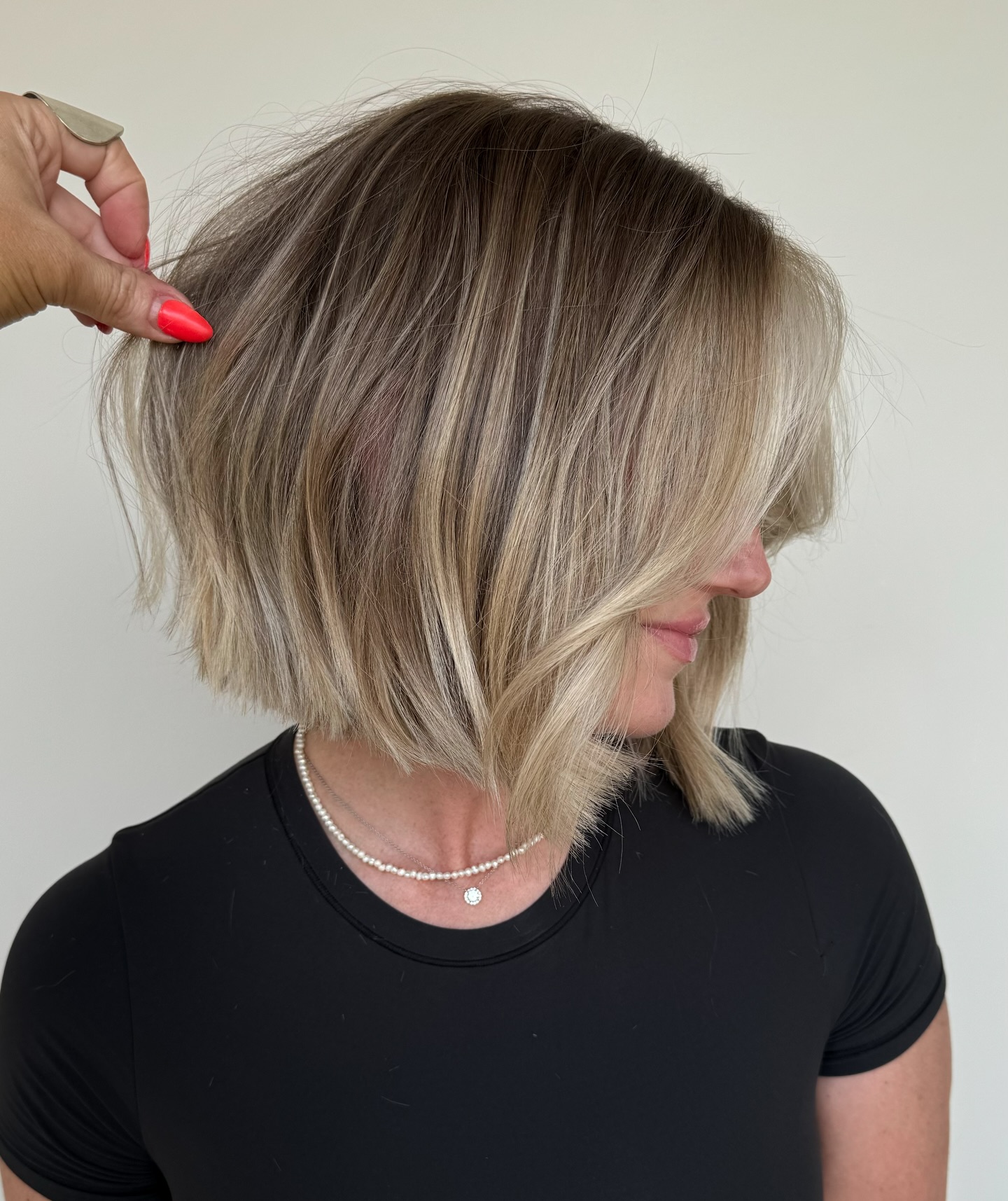 Stylist Texturizing a Textured Ash Blonde Bob with Fingers Side Profile View