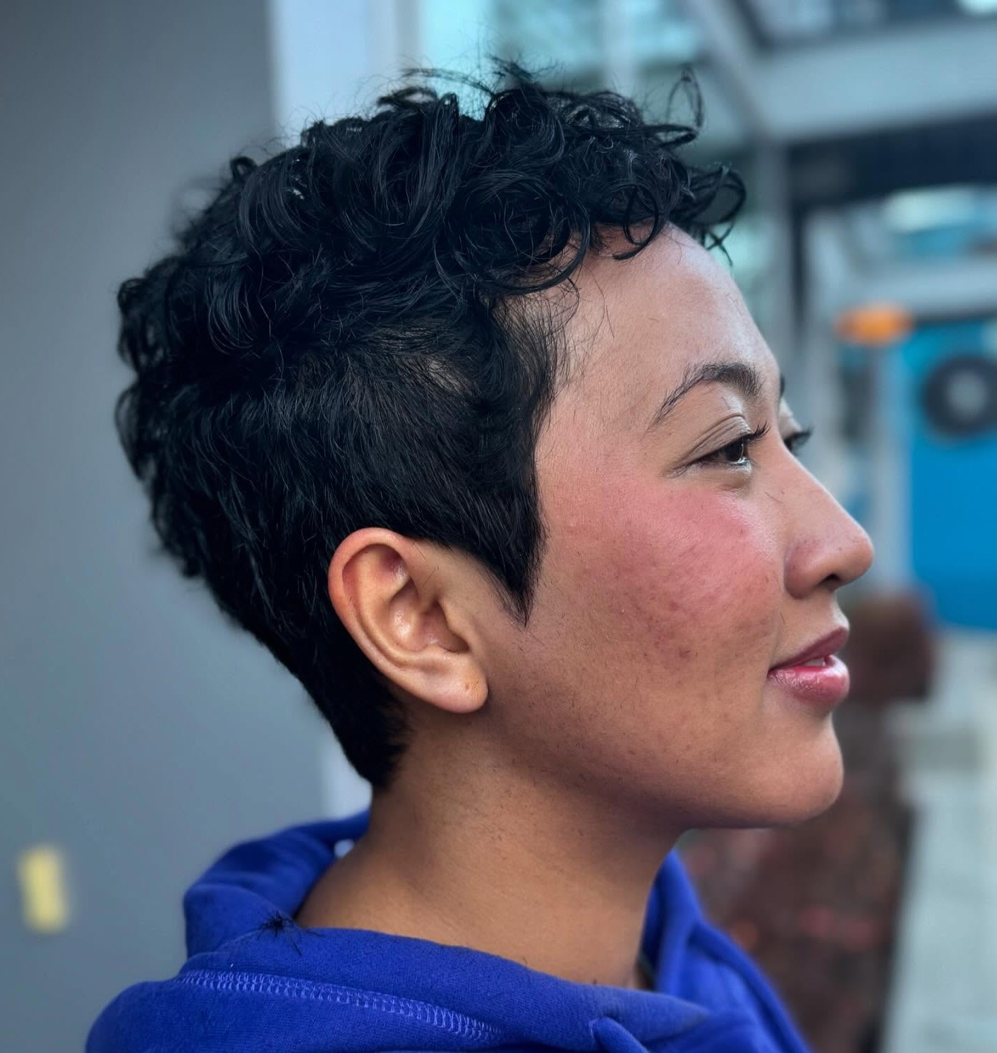 Discussing a Curly Pixie Cut Reference Photo During a Salon Consultation with a Hairstylist