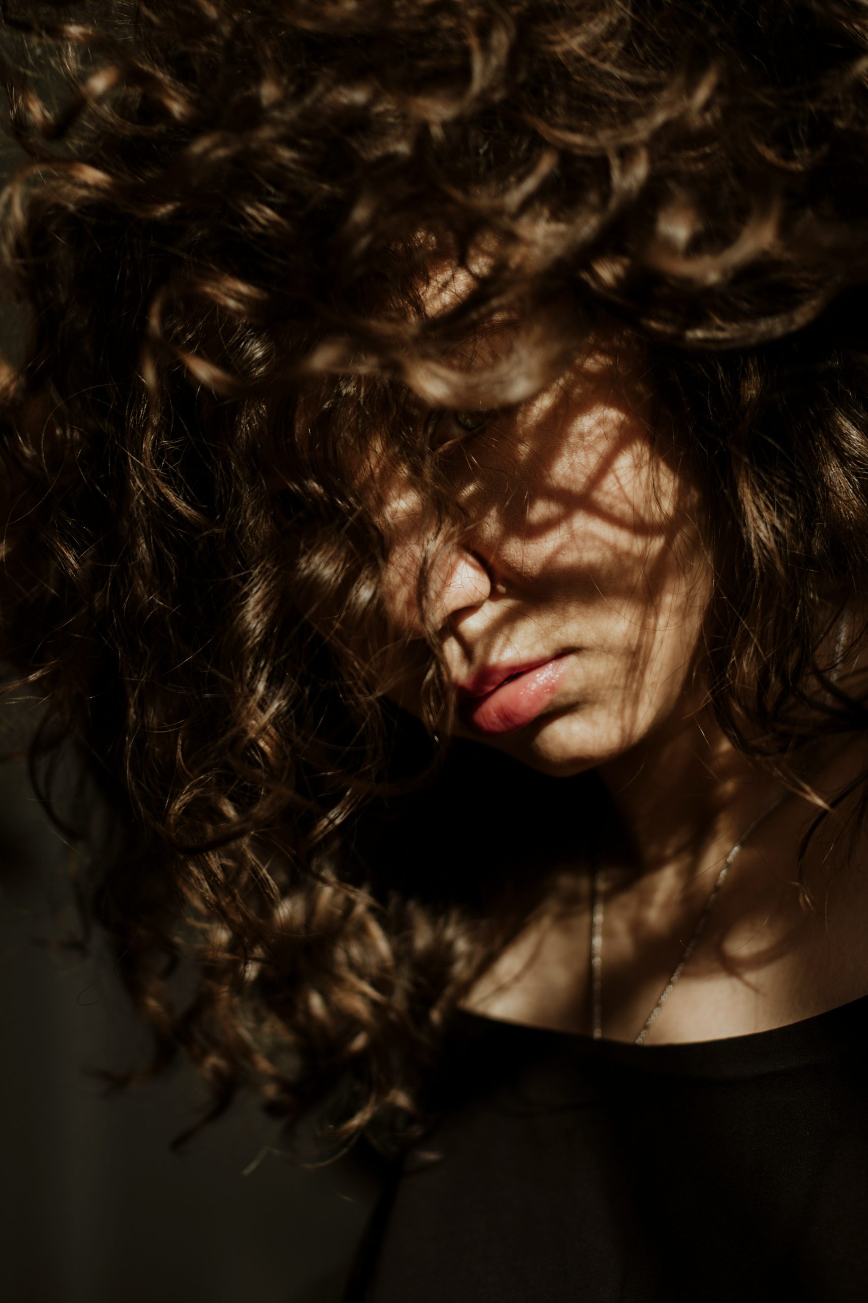 Curly Bangs Cut into a Soft Curtain Shape Framing the Face on Type 3 Brown Curls