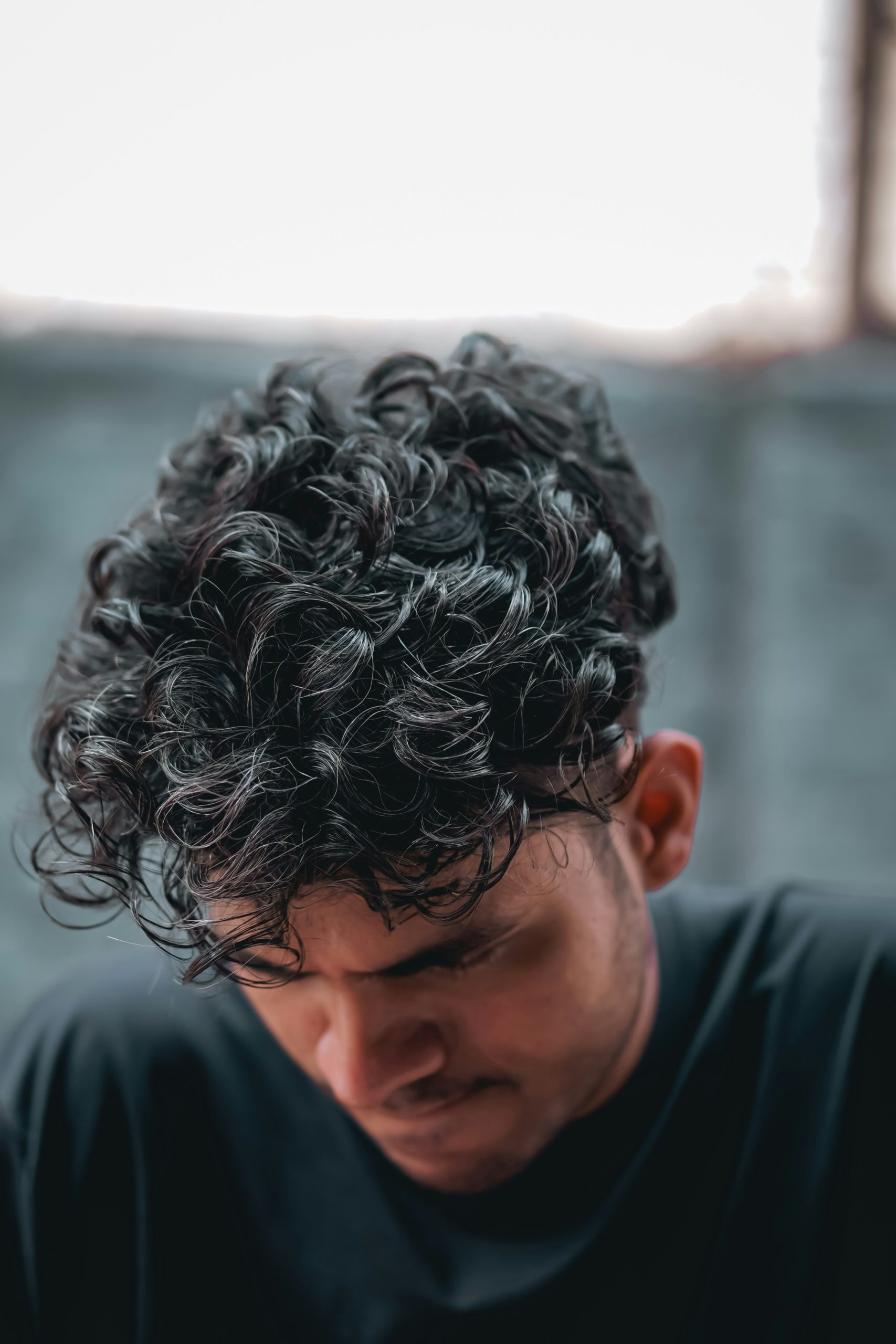 Curly Mullet Haircut on Man with Defined Ringlets and Short Tapered Sides