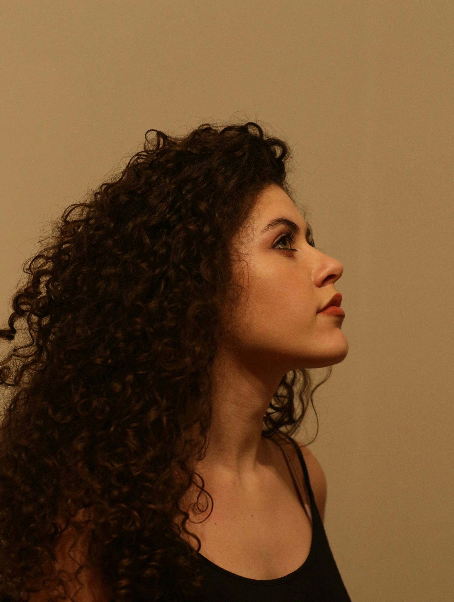 Curtain Bangs on Curly Hair Parted in the Middle and Framing the Face With Soft Coils