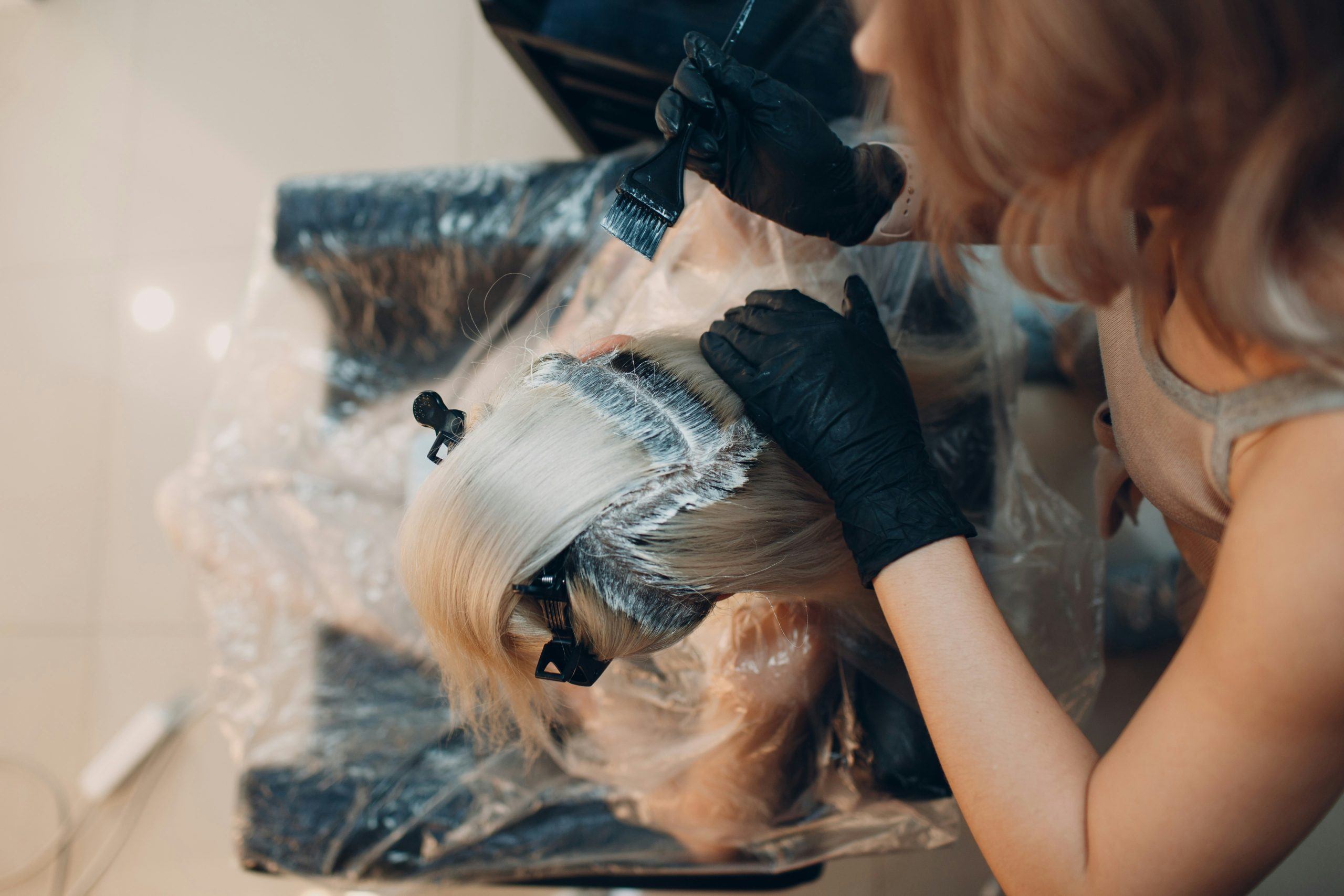 Hair Colorist Applying Color at the Roots to Demonstrate Lift and Hair Color Levels in a Salon