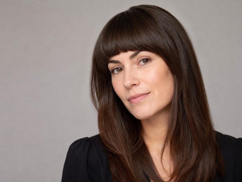 Arched Bangs Curving from a Short Center to Longer Temples on Dark Hair