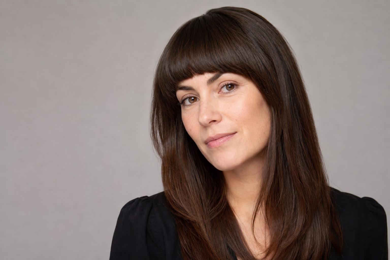 Arched Bangs Curving from a Short Center to Longer Temples on Dark Hair