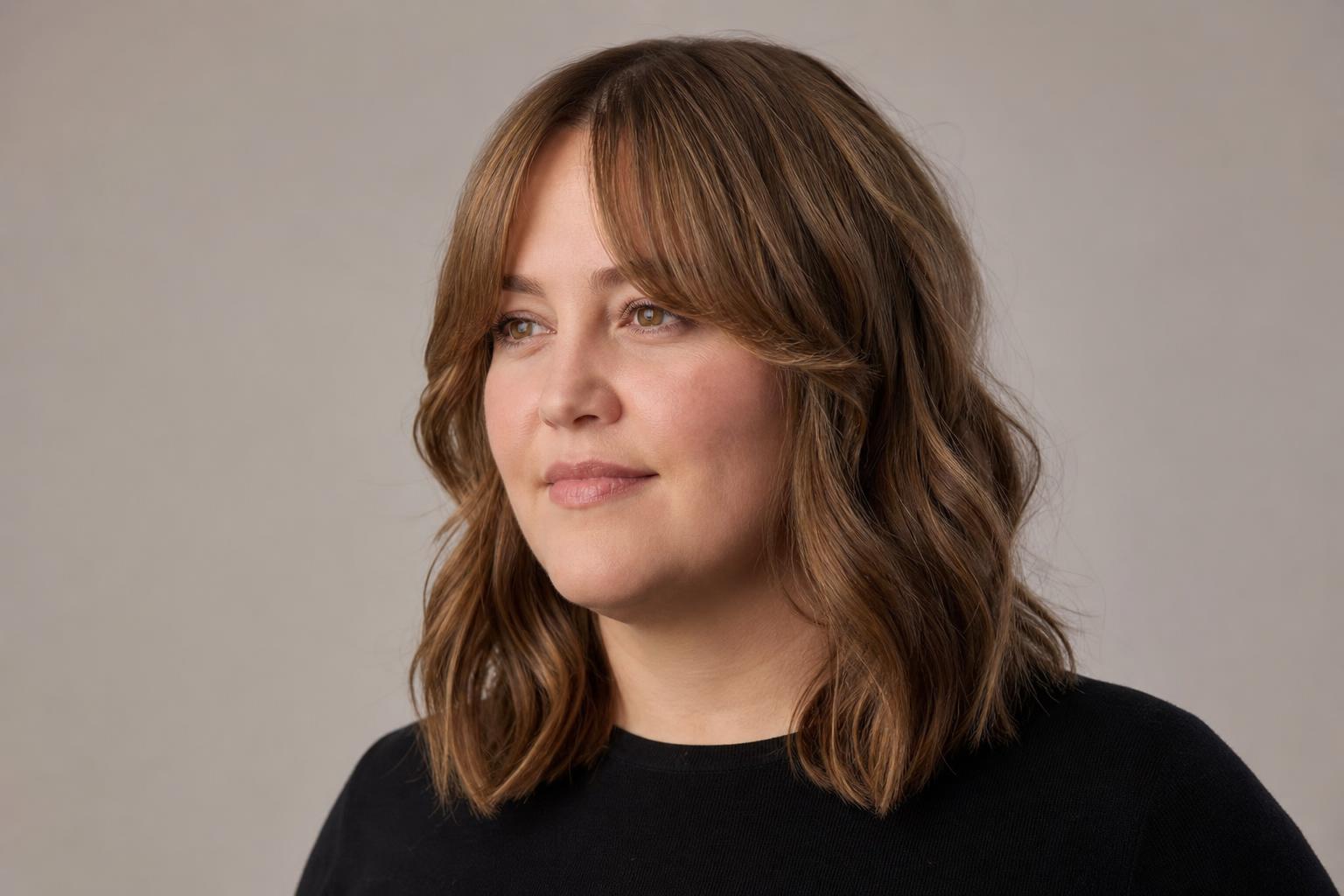 Curtain Bangs with a Short Center and Long Steep Sides Slimming a Round Face on Wavy Hair