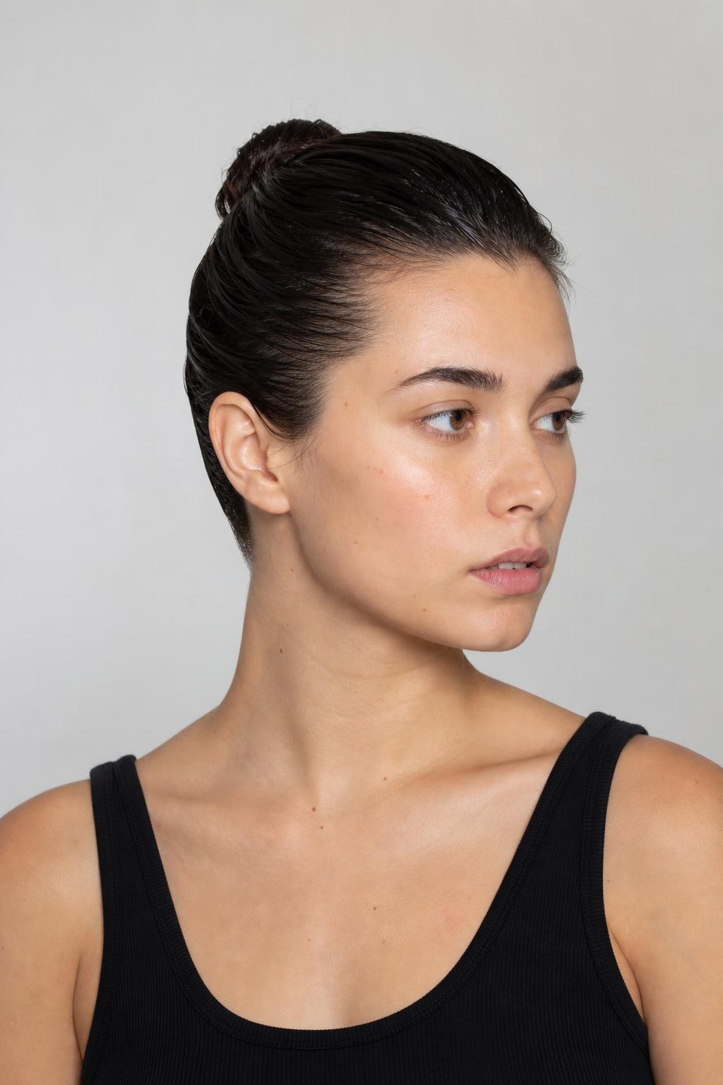 Slicked-Back Wet Bun Secured Tightly at the Crown on Dark Hair