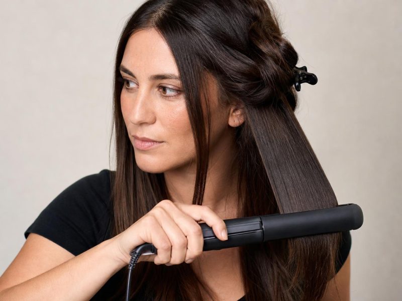 Ceramic Flat Iron Gliding Through a Clipped Section of Smooth Dark Brown Hair