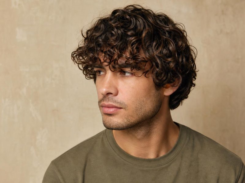 Medium-Length Curly Hair on a Man With Defined Curls Falling to the Ears