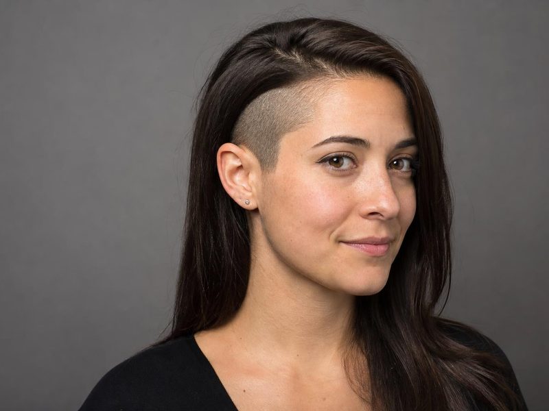 Long Dark Hair Tucked behind the Ear to Reveal a Curved Clipper-Shaved Undercut Panel